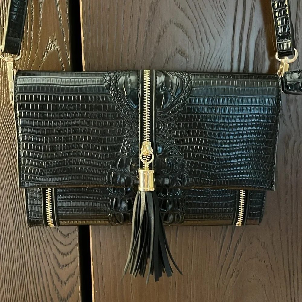 No brand black faux leather purse with black tassel and zippers for design.